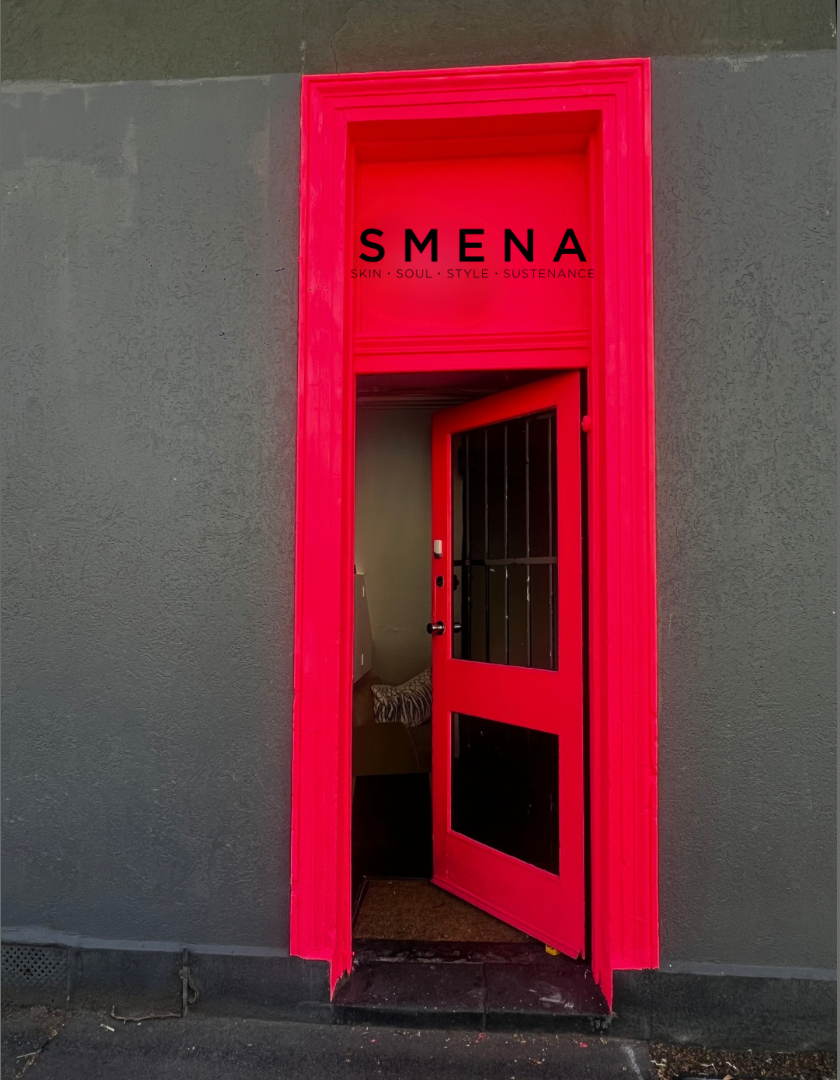 A bright hot pink painted doorway and matching door set against a textured gray wall, with the word 'SMENA' printed above the opening.